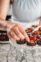 delicately placing chocolate dusted hazelnuts on top a nutella ganache dessert tart made fresh by tartlet bakery