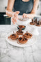 dusting cocoa powder over choc-orange tarts with dark chocolate shavings made fresh by tartlet bakery