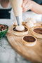 piping espresso whipped cream onto baked coffee filling tarts made fresh by tartlet bakery
