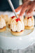 chef placing fresh raspberry on top of coconut and raspberry tart made from sweet shortcrust pastry, raspberry marshmallow filling, raspberry jelly, chantilly cream, sprinkled with roasted coconut and edible gold leaf