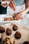 sprinkling roasted hazelnuts on top of whipped nutella ganache tart made fresh by tartlet bakery